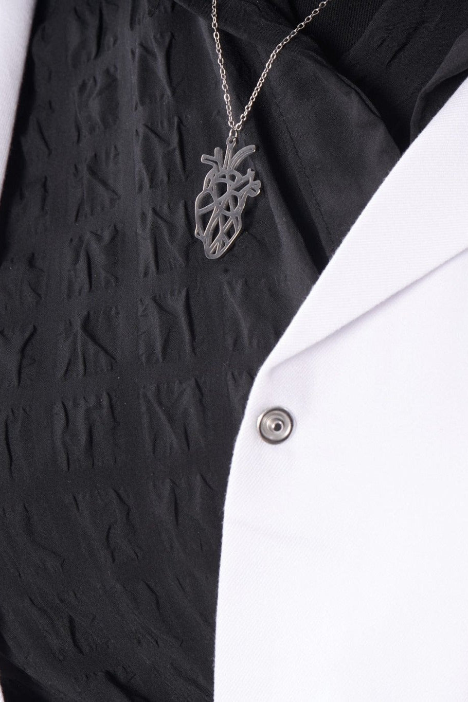 Silver anatomical heart pendant on model, BALTO lab coat