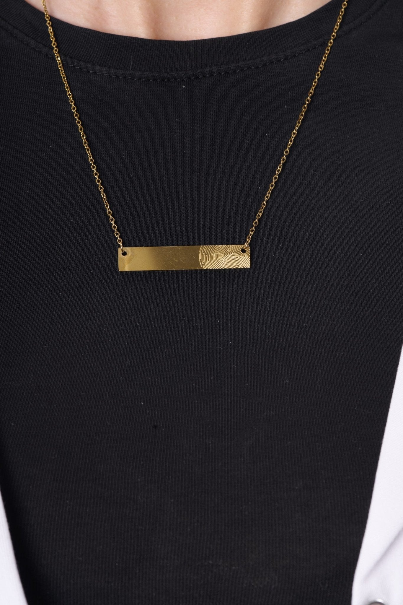 Fingerprint bar necklace worn with a BALTO lab coat