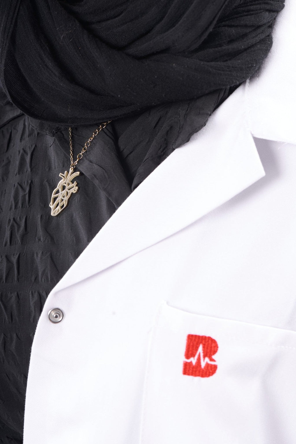 Gold anatomical heart pendant on model, BALTO lab coat