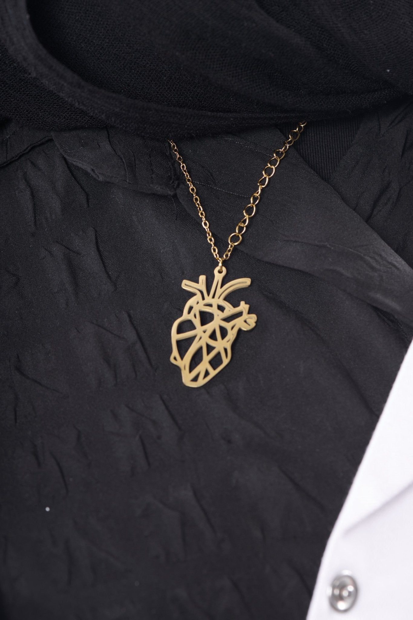 Gold anatomical heart pendant worn with a BALTO lab coat