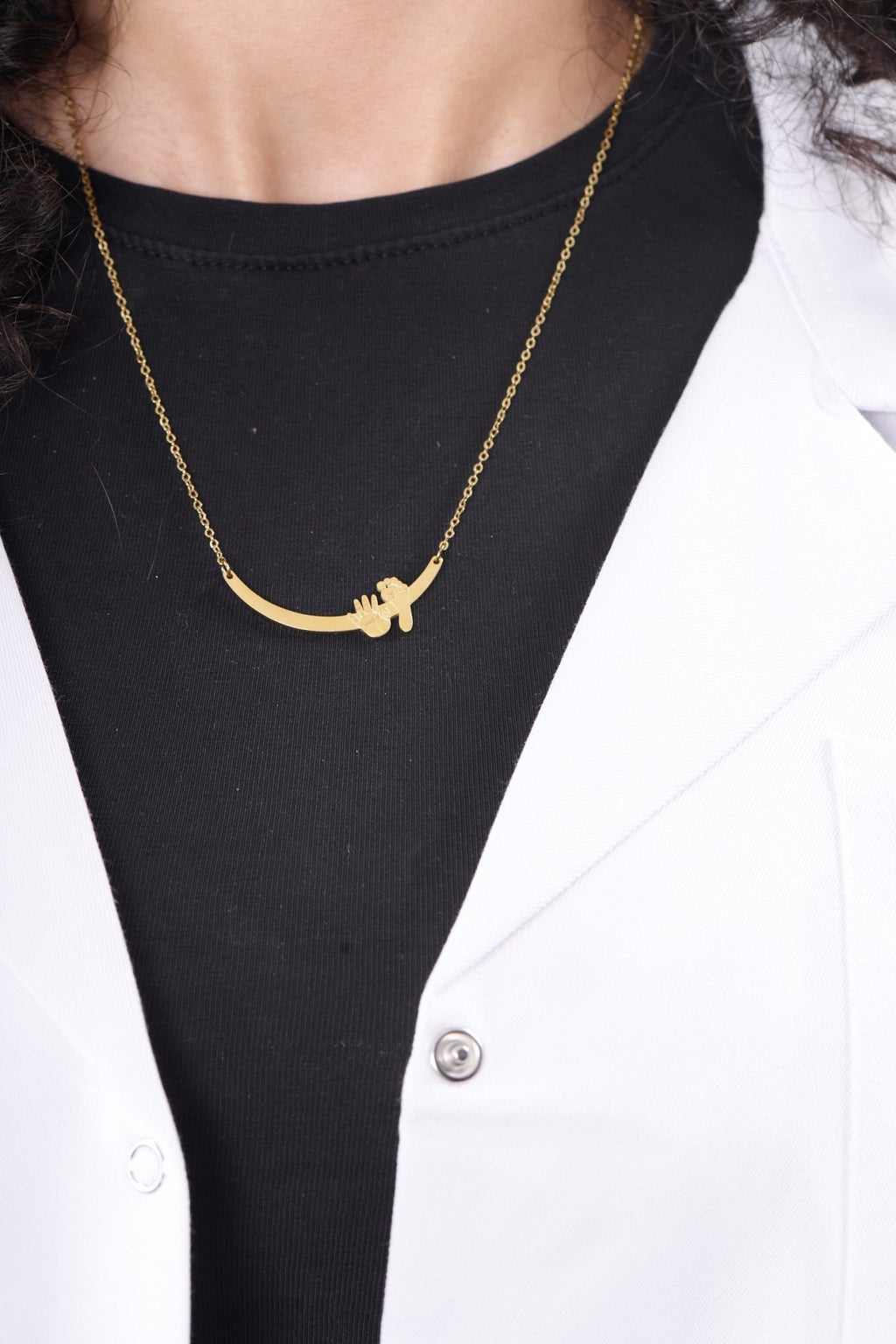 Hand and foot necklace worn with a BALTO lab coat