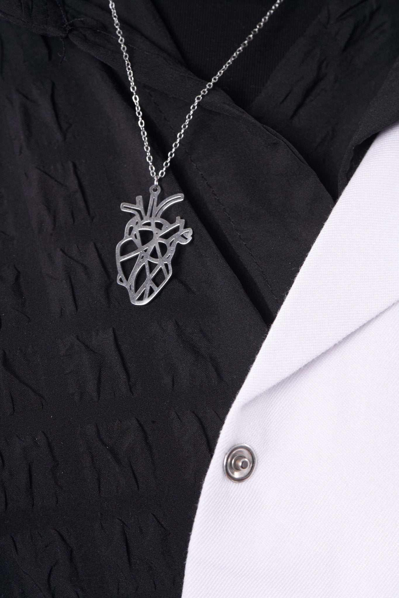 Silver anatomical heart pendant worn with a BALTO lab coat